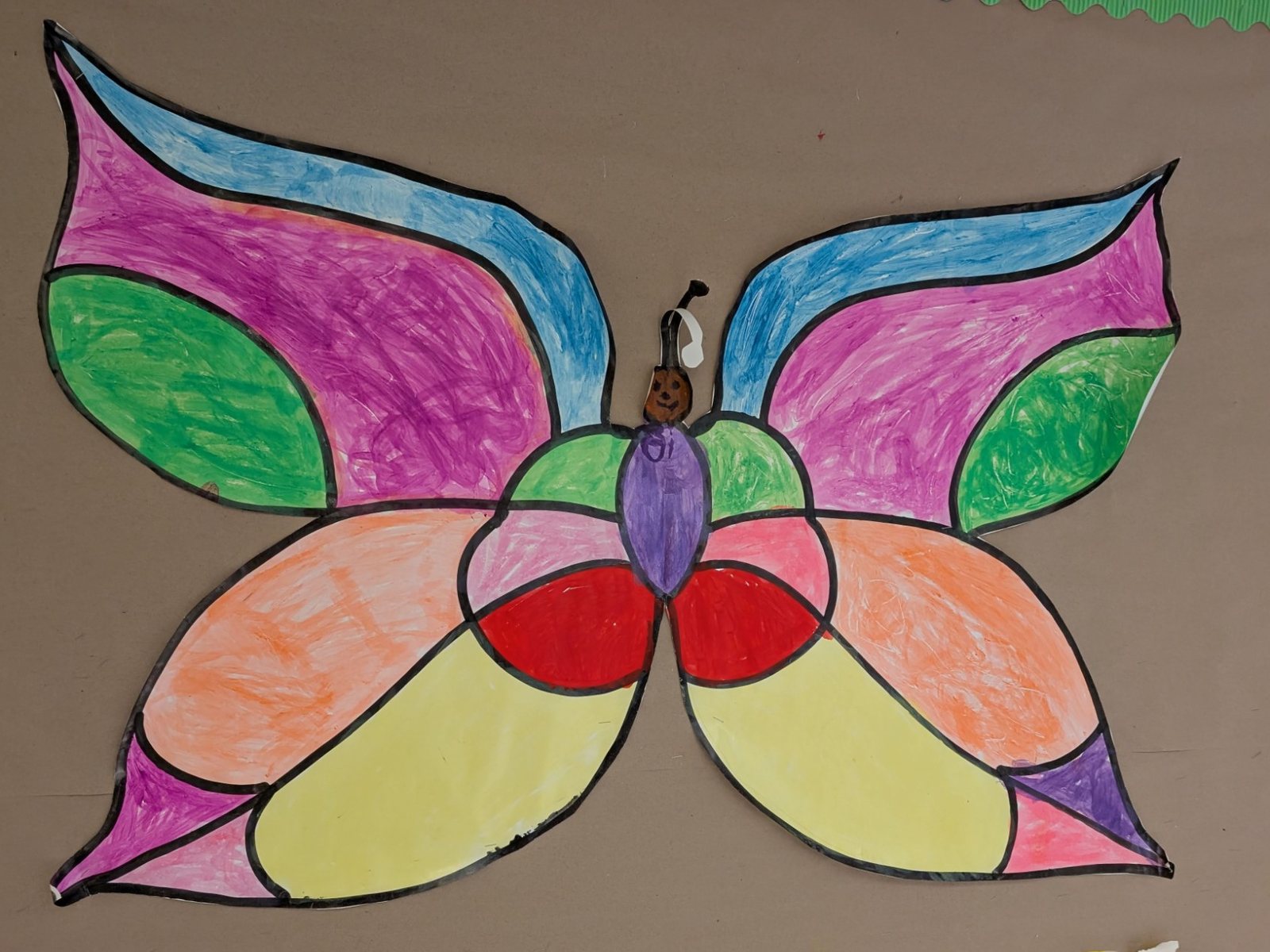 A butterfly with bold black outlines, its wings coloured in with pink, blue, green, orange, yellow and red marker