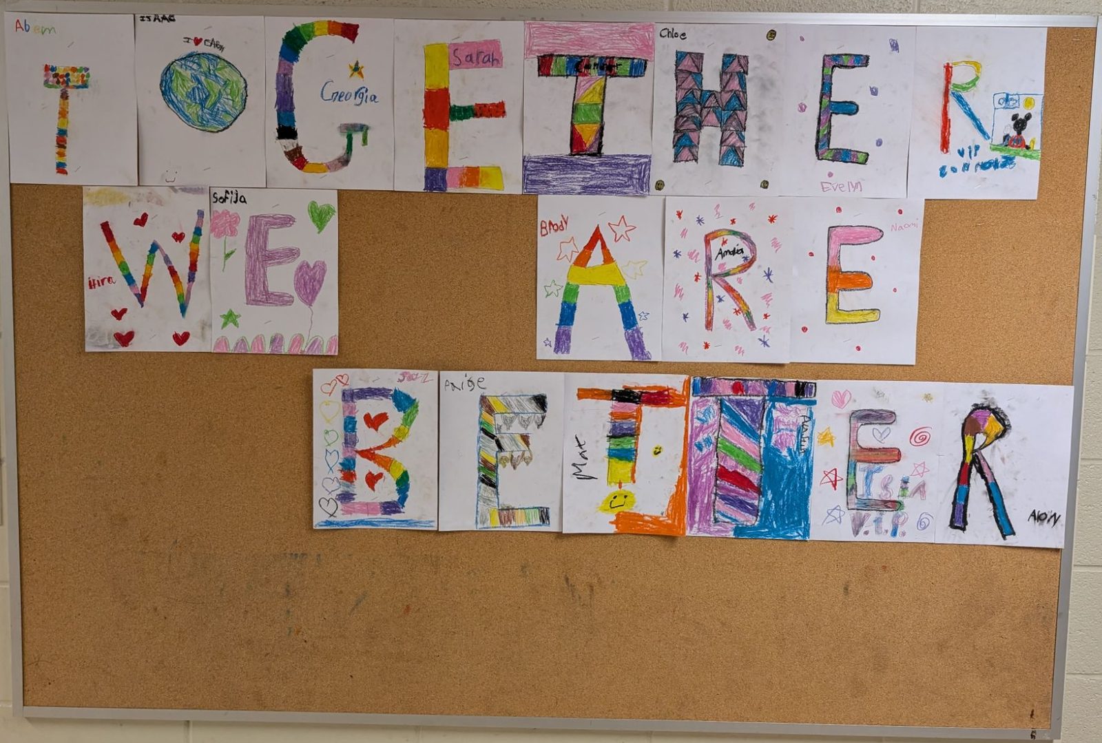Hand-coloured letters from many students spelling out Together We Are Better across a bulletin board
